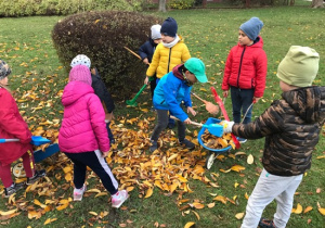 Dzieci grabią liście na placu zabaw