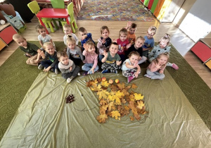 Dzieci z ułożonym jeżem z liści i kasztanów