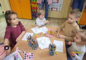 Dzieci przy stoliku kolorują obrazki dinozaurów