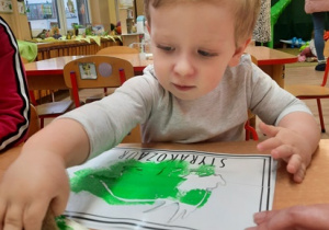 Chłopiec maluje farbami dinozaura