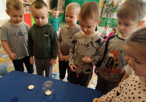 Dzieci wykonują eksperyment ze świeczką i słoikiem