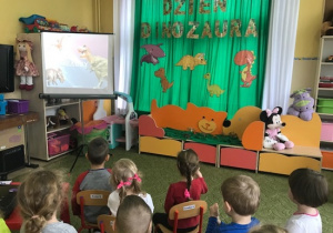 Dzieci oglądają prezentację multimedialną o życiu dinozaurów