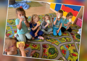 Dzieci z grupy Jeżyków piją wodę z kubeczków na dywanie