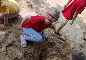 Dzieci próbują odkopać szkielet dinozaura