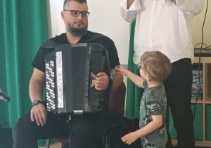 Chłopiec przykręca śrubkę przy harmonii.