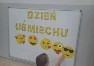Chłopiec pokazuje emotki na tablicy.