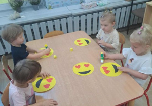 Dzieci tworzą prace plastyczną - emotkę.