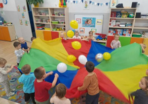 Dzieci podrzucają balony na chuście animacyjnej.