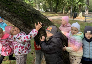 Dzieci przytulają się do drzewa.