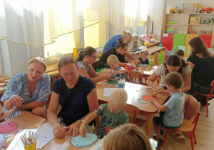 Rodzice z dziećmi wykonują pracę plastyczną.