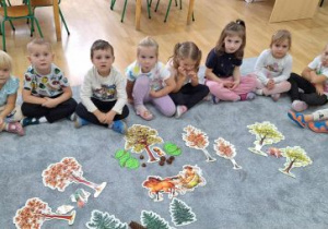 Dzieci oglądają ilustracje różnych drzew.