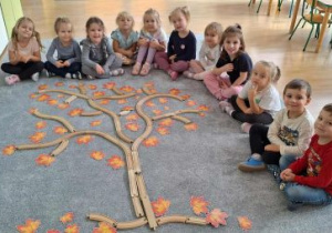 Dzieci ułożyły jesienne drzewo z drewnianych klocków.