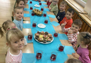 Dzieci siedzą przy stole pełnym smacznych przekąsek.