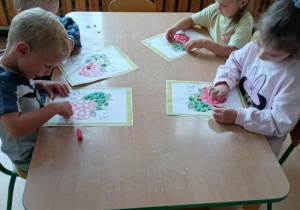 Dzieci wylepiają plasteliną szablon jabłka.