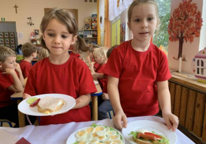 Dziewczynki prezentują samodzielnie wykonane kanapki.