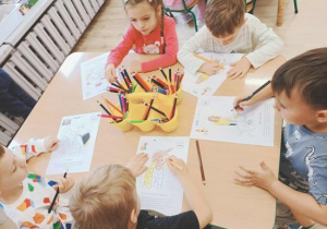 Dzieci kolorują kolorowankę z pieskami.