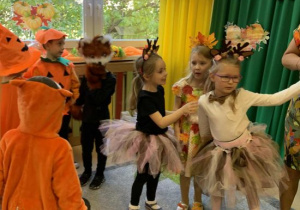 Dzieci w jesiennych przebraniach tańczą w rytm muzyki.