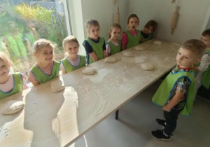 Dzieci stoją z przygotowanym ciastem na chleb.