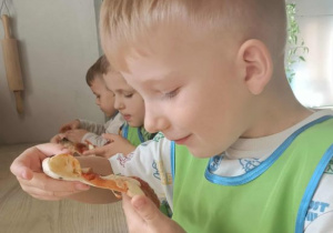 Maks trzyma smaczny kawałek pizzy.