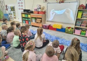 Dzieci oglądają film jak złożyć rybkę z papieru.