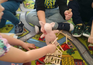 Dzieci budują chatkę z patyczków.