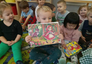 Chłopiec pokazuje ilustrację z bajki o Czerwonym Kapturku.