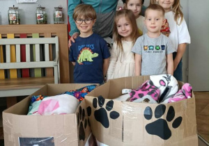 Dzieci stoją z Panią Anią z darami dla zwierząt.