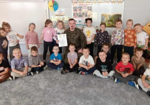 Grupowe zdjęcie dzieci z żołnierzem.