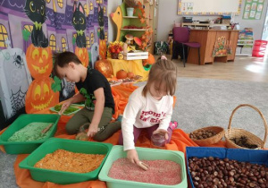 Dzieci wsypują kolorowy ryż do słoików.