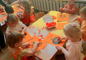Dzieci wyklejają dynię kawałkami bibuły.