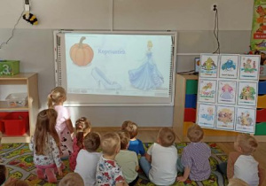 Dzieci oglądają film edukacyjny o postaciach z bajek.