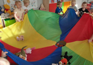 Dzieci podrzucają na chuście animacyjnej pluszaki.