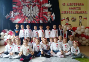 Zdjęcie grupowe dzieci z grupy Pszczółek na tle dekoracji z okazji Święta Niepodległości.