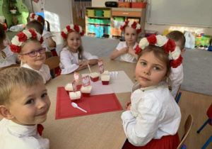 Dzieci siedzą przy stole przed biało-czerwonym deserem.