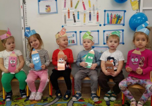 Dzieci trzymają kolorowe kredki.