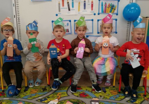 Dzieci trzymają kolorowe kredki.