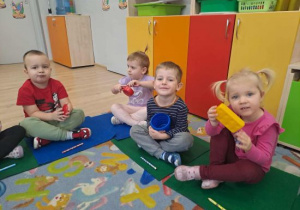 Dzieci trzymają kolorowe przedmioty.