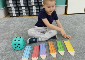Chłopiec przelicza kolorowe kredki.