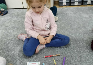 Dziewczynka układa kredki wg wzoru.