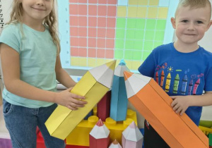 Dzieci pokazują papierowymi kredkami zakodowane kredki.