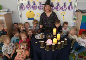 Grupowe zdjęcie dzieci wokół andrzejkowego stołu.