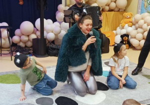 Dzieci w przebraniu kotów słuchają śpiewu Pani z filharmonii.