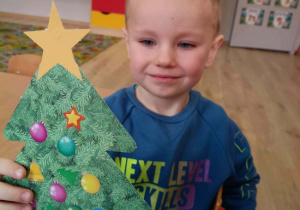 Chłopiec prezentuje wykonaną przez siebie choinkę.