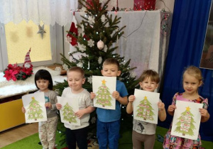 Dzieci pokazują wykonane przez siebie choinki.