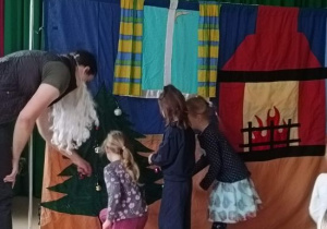 Dzieci z aktorem ubierają choinkę na scenie.