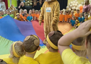 Teddy Eddie bawi się z dziećmi na chuście animacyjnej.