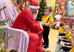 Mikołaj wręcza prezent Pawełkowi.