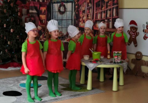 Dzieci w strojach kucharzy śpiewają piosenkę.
