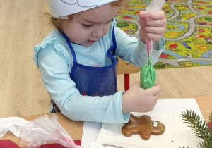 Dziewczynka dekoruje lukrem piernika.