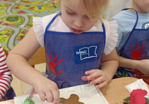 Dziewczynka dekoruje lukrem piernika.